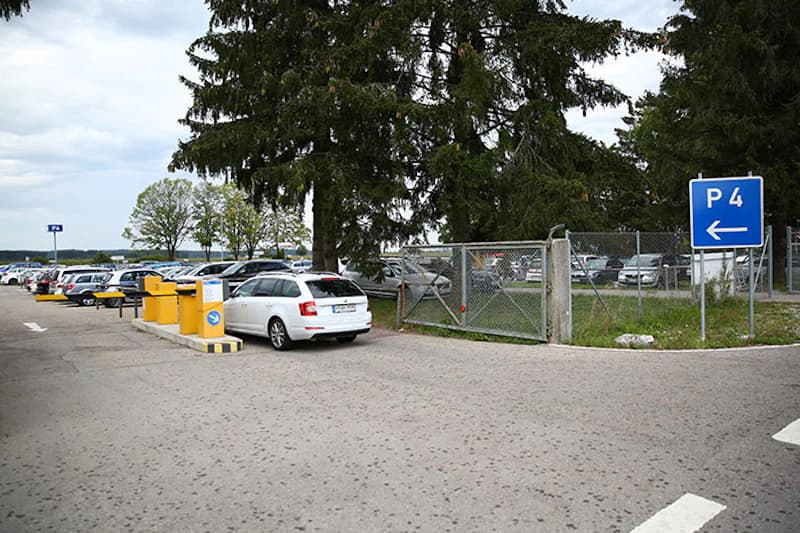 Parkplatz mit mehreren geparkten Autos, Schrankenanlage und blauem P4-Schild am Flughafen Memmingen.
