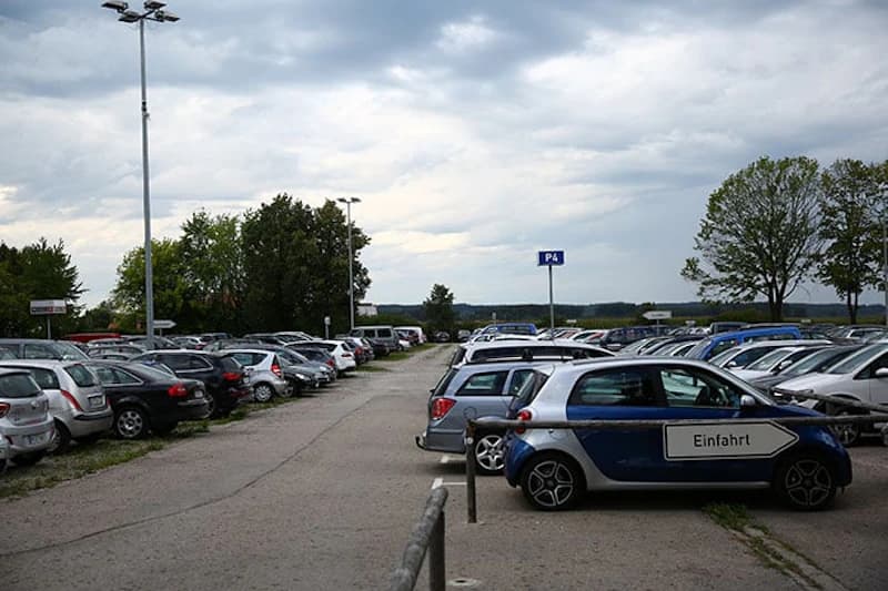 Großer Außenparkplatz mit Reihen geparkter Autos und Schild P4 am Flughafen Memmingen.