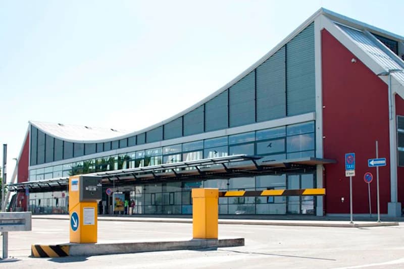 Gelber Zufahrtsbalken und Automat vor dem gewellten Terminal des Flughafens Memmingen.