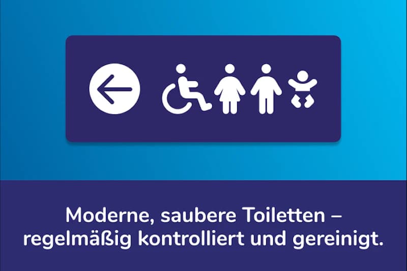 Schild mit Pfeil nach links und Symbolen für Rollstuhl, Damen, Herren und Wickelraum über Text zu modernen sauberen Toiletten.