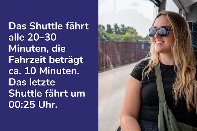 Frau mit Sonnenbrille sitzt in einem Shuttle neben einer blauen Tafel mit Fahrplantext.