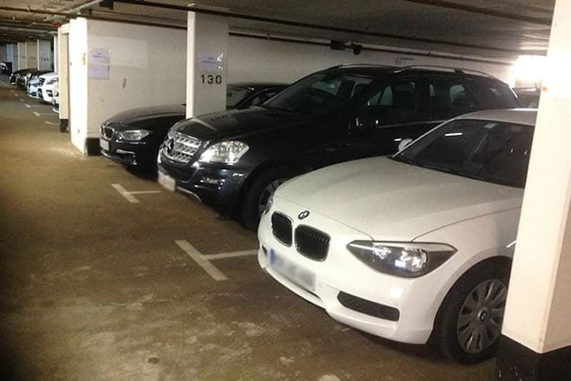 Tiefgarage mit mehreren geparkten Autos neben Säulen mit der Nummer 130.