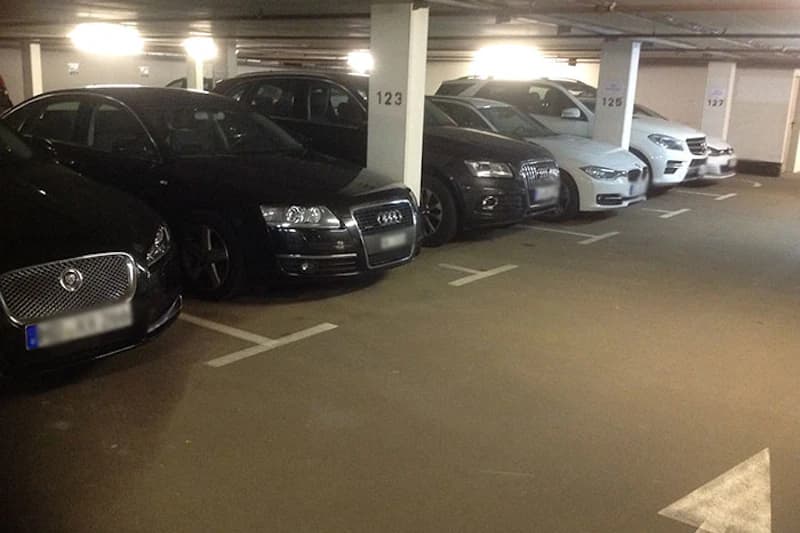 Tiefgarage mit nebeneinander geparkten Fahrzeugen an markierten Stellplätzen, Säulen mit Nummern 123, 125 und 127.