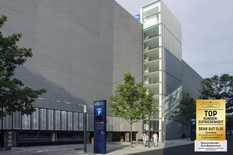 Mehrstöckiges Parkhaus mit silberner Lamellenfassade, gläsernem Treppenturm, Eingangsbereich und zwei Fußgängern am Flughafen Frankfurt.