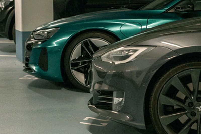 Vorderseiten mehrerer geparkter Autos mit Scheinwerfern und Rädern in einer beleuchteten Tiefgarage.