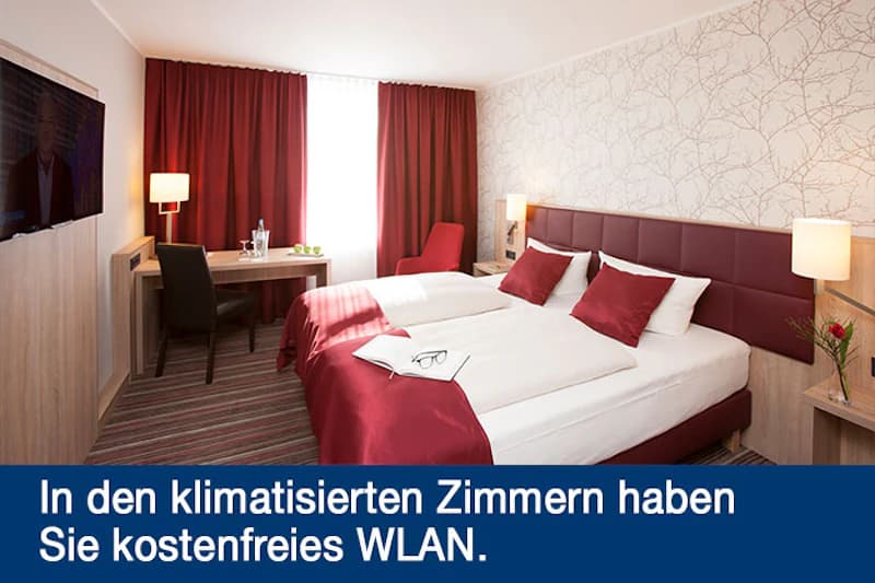 Hotelzimmer mit zwei zusammengestellten Betten, rotem Bettüberwurf und Vorhängen, Schreibtisch, Fernseher und Nachttischlampen.
