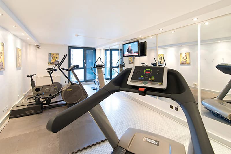 Kleiner Fitnessraum mit Laufband, Fahrrad-Ergometer, Crosstrainer, Spiegelwand und Fernseher.