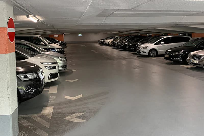 Tiefgaragenebene mit zwei Reihen geparkter Autos, Pfeilmarkierungen auf dem Boden und Einfahrtsverbotsschild an einer Säule.