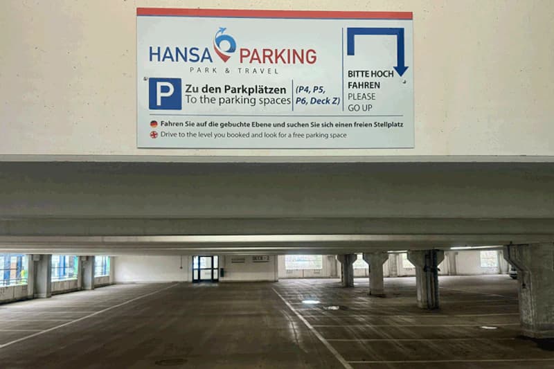 Leeres mehrgeschossiges Parkhaus mit Hansa Parking Schild über der Einfahrt und sichtbaren Stützpfeilern.