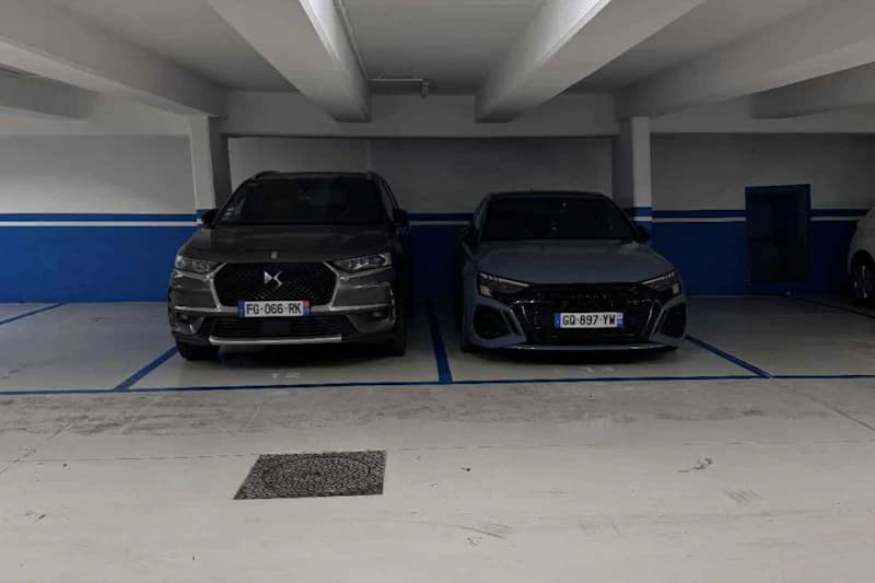 Zwei nebeneinander geparkte Autos in beleuchteter Tiefgarage mit blauen Parklinien und sichtbaren Kennzeichen.