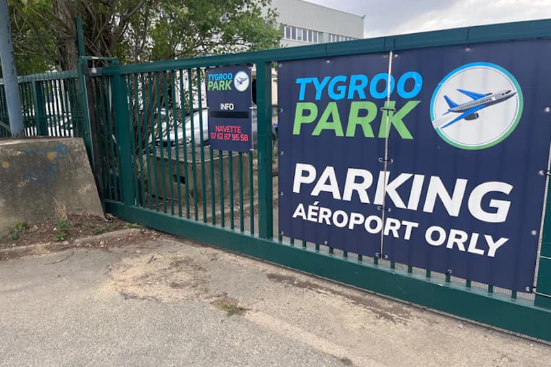 Grünes Metalltor mit Bannern von Tygroo Park und Hinweis auf Flughafen Orly.