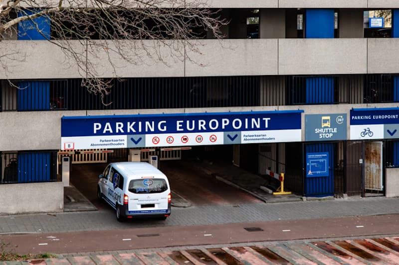 Mehrgeschossige Parkhauszufahrt mit Schild PARKING EUROPOINT und weißem Shuttlefahrzeug an der Einfahrt.