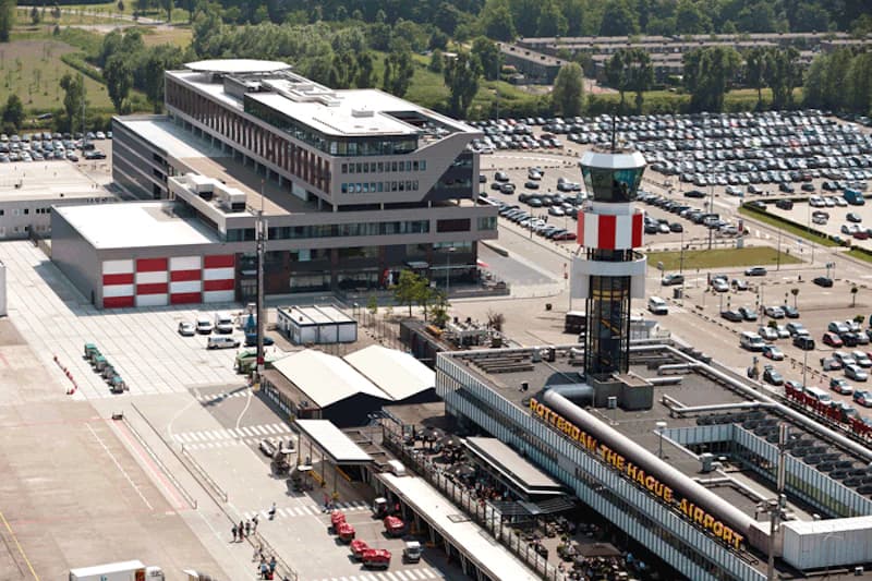 Terminalgebäude mit Kontrollturm und großem Parkplatz am Rotterdam The Hague Airport.
