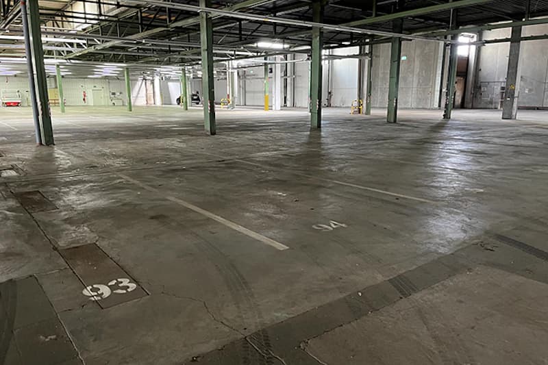 Leere Parkhalle mit nummerierten Stellflaechen 33 und 34, Betonboden und Stahlpfeilern.