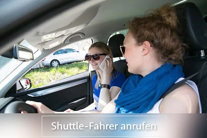 Zwei Frauen im Auto, Beifahrerin telefoniert, auffälliger Schriftzug unten im Bild.