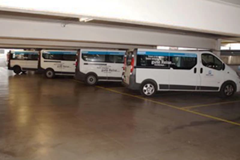Dunkles Parkhaus mit drei weißen Shuttle-Bussen nebeneinander geparkt.