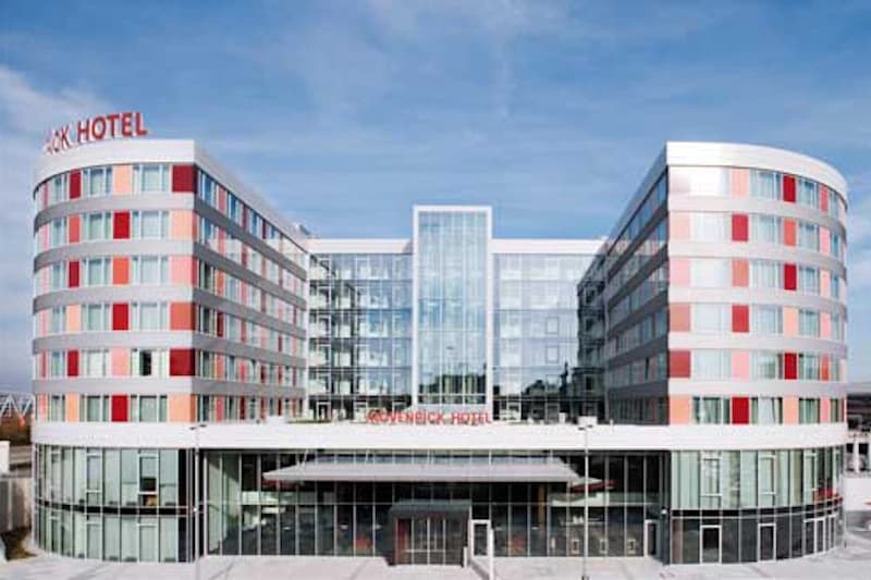 Fassade des Mövenpick Hotel Stuttgart Airport mit zwei runden Flügeln und verglaster Mittelzone.