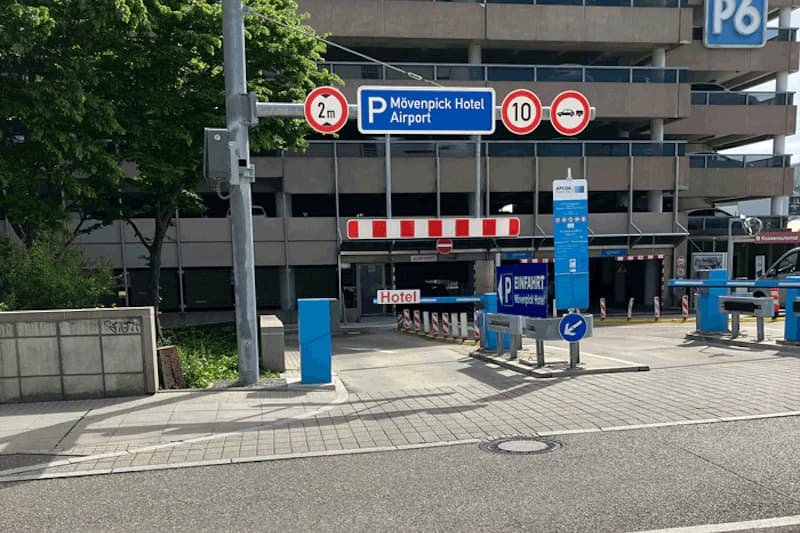 Einfahrt zum Parkhaus mit Schranke, Parkschild Mövenpick Hotel Airport, Höhenbegrenzung 2 m und Parkautomaten sichtbar.