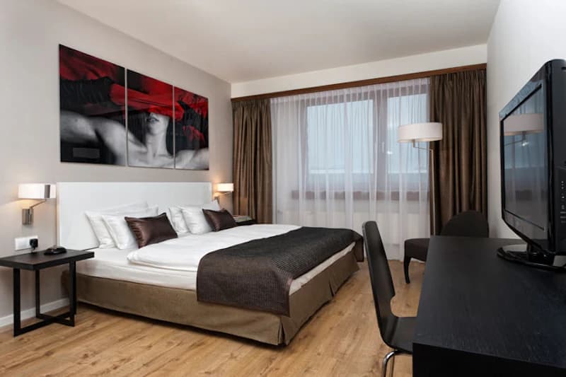Doppelzimmer mit großem Bett, Wandbild, Nachttischen, Stehlampe, Schreibtisch und Fernseher.