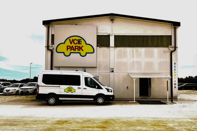 Zweistöckiges Parkhaus mit großem VCE PARK Schild und weißem Shuttlevan mit Logo vor dem Empfangseingang.
